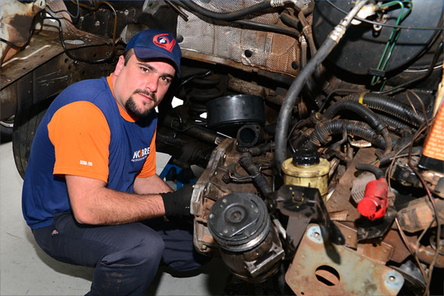 Técnico de motores inspecionando peças dentro de um carro